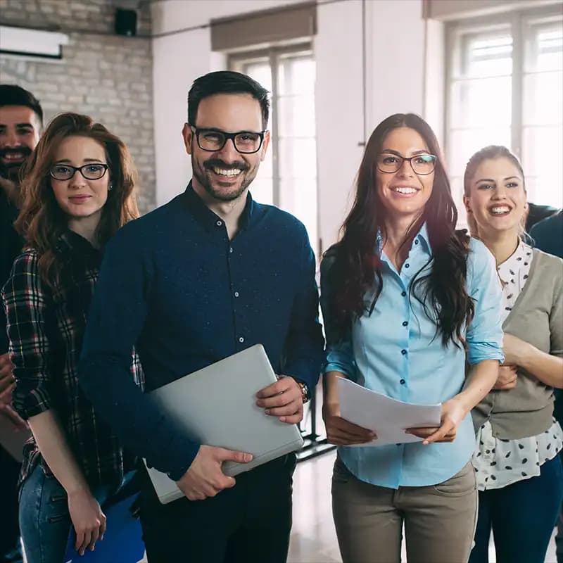 Eine Gruppe von glücklichen Fachkräften in Business-Kleidung, die Selbstvertrauen und Erfolg ausstrahlen.